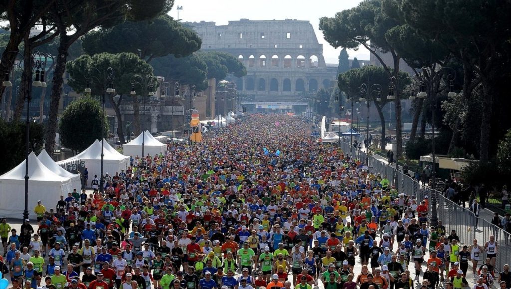 Migliaia di runner percorrono i Fori Imperiali durante la Maratona di Roma, con il Colosseo sullo sfondo